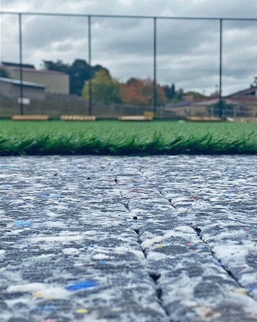 Before the synthetic grass can be rolled out, a modular shock pad layer is installed.