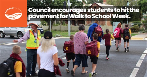 School crossing supervisor stops traffic while parents and school children cross the street